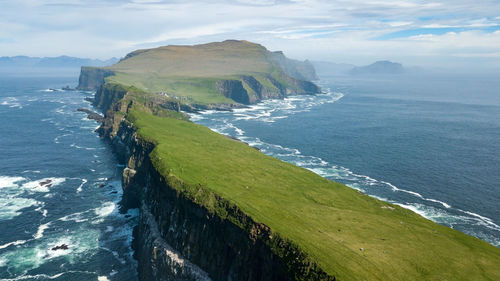 Aerial view of cliff by sea against cloudy sky