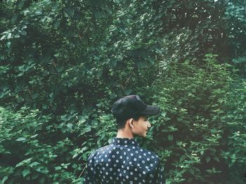 Rear view of young man standing against trees