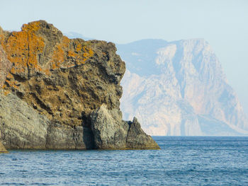 Rock formations by sea against clear sky