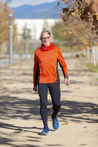 Portrait of senior man running on road during autumn