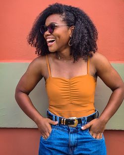 Portrait of young woman standing against yellow wall