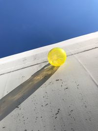 Low angle view of yellow ball against blue sky