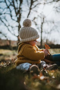 Mother and daughter wearing warm clothing while sitting on land