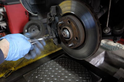 Cropped hands of male mechanic repairing car in auto repair shop