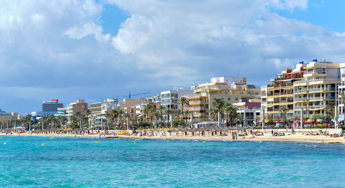 View of buildings at waterfront against cloudy sky