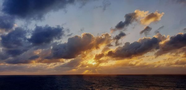 Scenic view of sea against dramatic sky during sunset