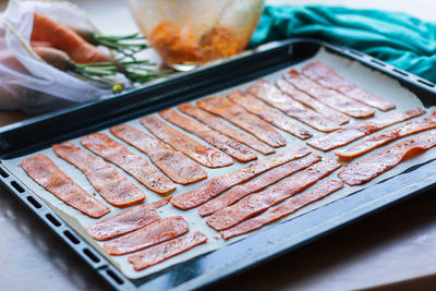 Sliced carrots are lying on parchment paper on a protvin for cooking carrot bacon. meat replacement