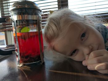 Close-up portrait of a girl with drink on table