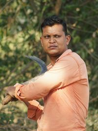 Man holding weapon standing against trees in forest