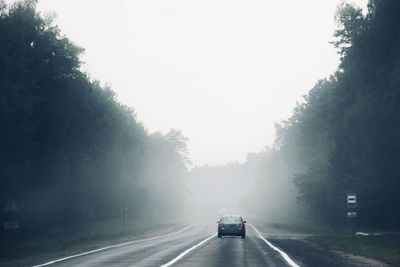 Car on road against sky on a misty day 