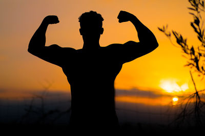 Silhouette man standing against orange sky during sunset