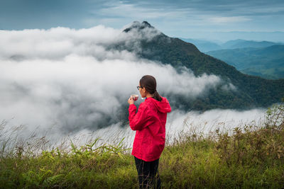 Rear view of woman standing on mountain during foggy weather