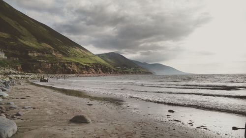 Scenic view of beach against cloudy sky