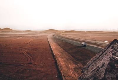 Scenic view of desert road against clear sky