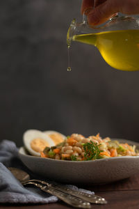 Pouring olive oil on beans salad. healthy nutrition concept