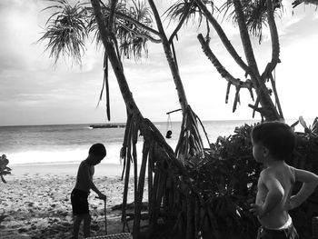 Boy and palm trees on beach against sky