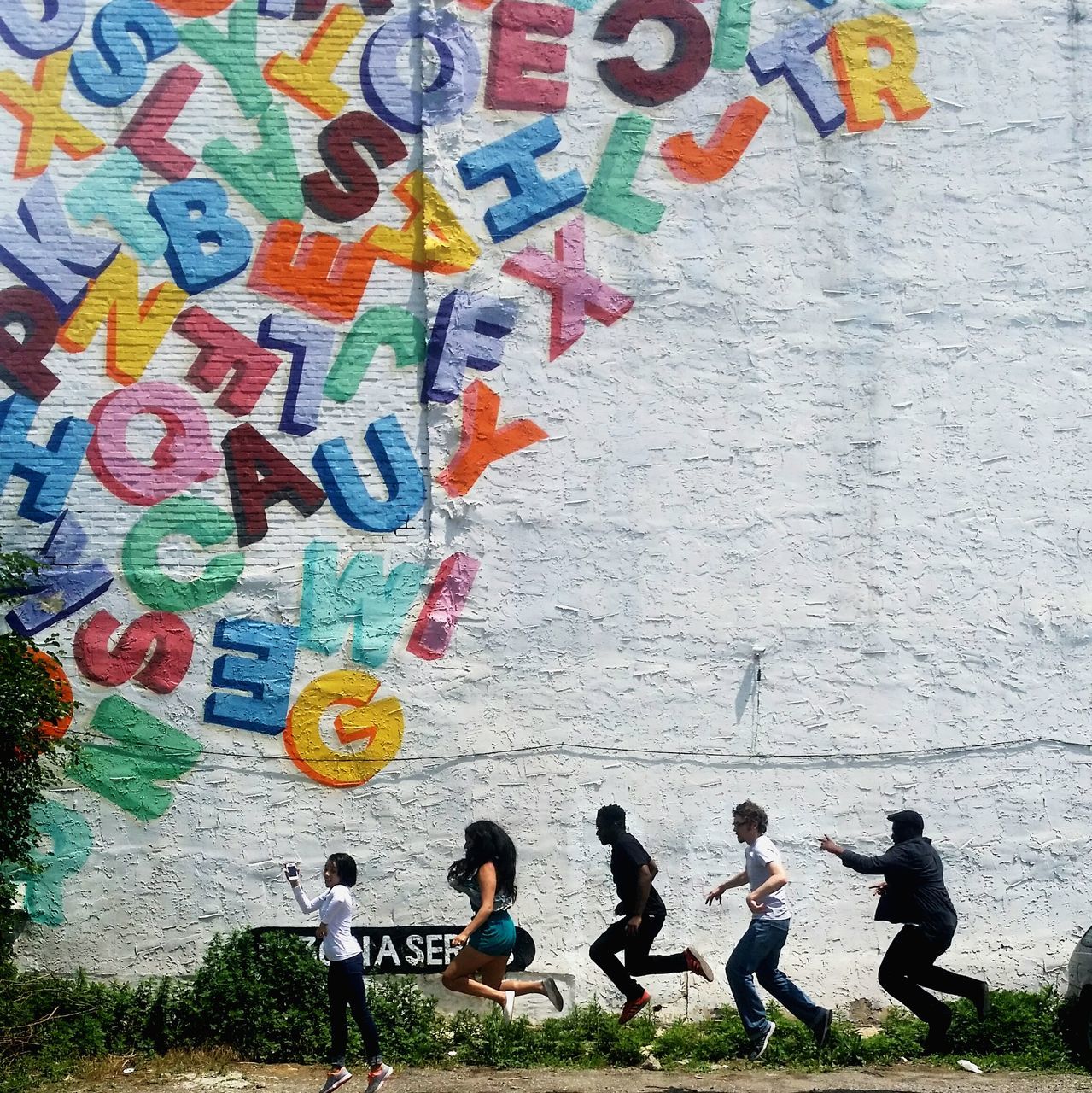 lifestyles, leisure activity, men, high angle view, wall - building feature, architecture, built structure, person, childhood, boys, building exterior, togetherness, day, street, full length, casual clothing, graffiti, outdoors, large group of people