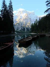 Boats moored on lake by mountain against sky