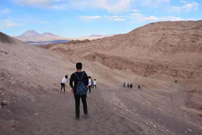 Full length of man and woman walking on desert against sky