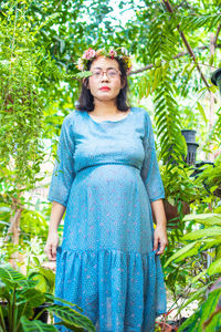 Portrait of young woman standing against plants