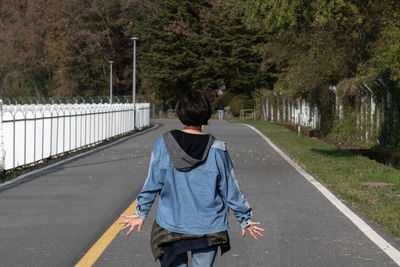 Rear view of woman walking on road