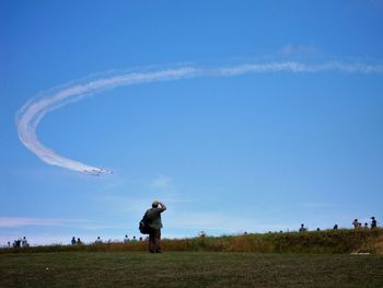 Man standing on field against blue sky