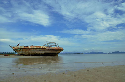 Abandoned boat on beach against sky