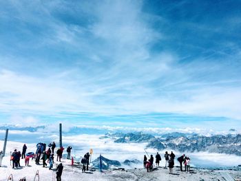 Group of people on snow covered land against sky