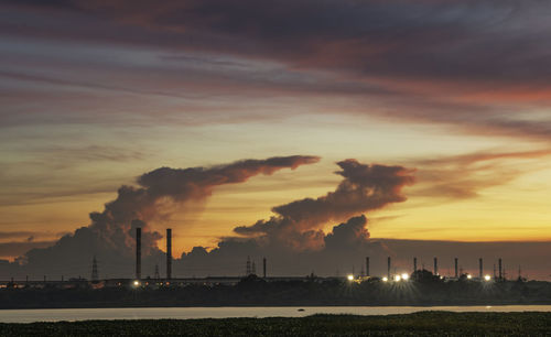 Scenic view of factory against sky during sunset.