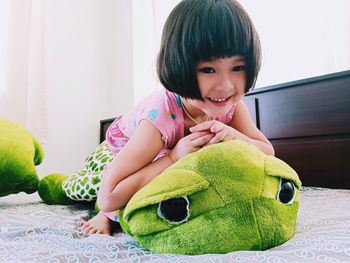 Portrait of cute girl sitting on bed at home