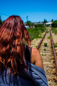 Rear view of woman with railroad tracks against sky