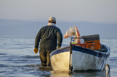 Rear view of man working at sea against sky