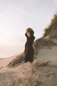 Woman standing on sand at beach against sky