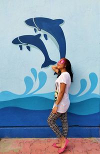 Full length of woman standing against mural wall