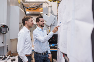 Two men in factory looking at plan