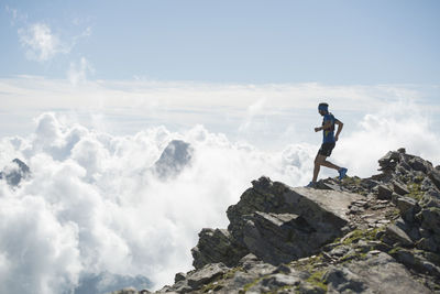 Man standing on rock against sky