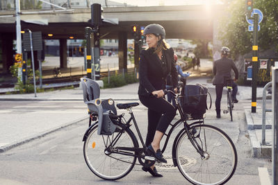 Businesswoman with bicycle on street in city