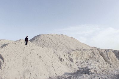Low angle view of man standing on mountain at desert against sky