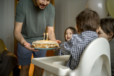 Cheerful family together celebrating son's birthday at home