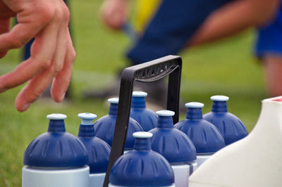 Cropped hand reaching blue bottles outdoors