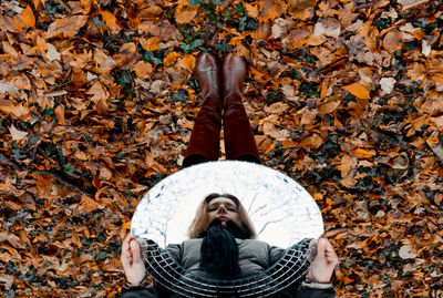 Woman with mirror on dry leaves in forest