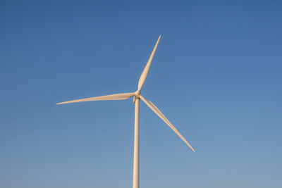 Low angle view of windmill against blue sky