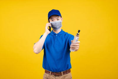 Full length portrait of boy standing against yellow background