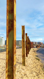 Wooden posts on beach by city against sky