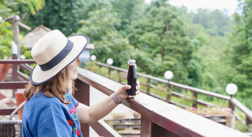 Rear view of woman with hat on railing