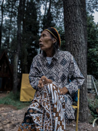 Old man enjoying the natural atmosphere in the forest.wearing a typical indonesian batik shirt