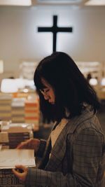 Side view of woman reading book at table