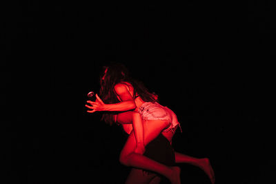 Midsection of woman with red hair against black background