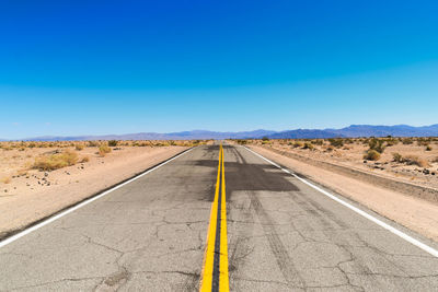 Road passing amidst landscape against clear blue sky