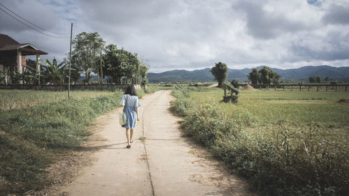 Rear view of two people walking on road